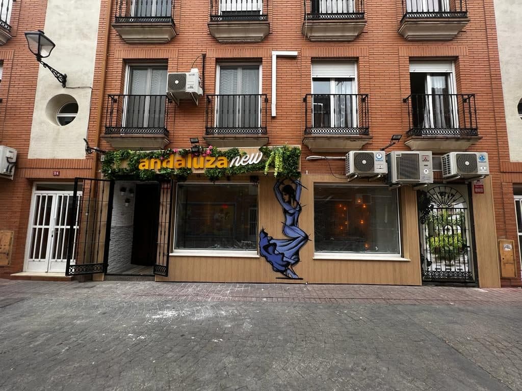 Fachada de La Andaluza New con su rótulo verde y el mural de una flamenca