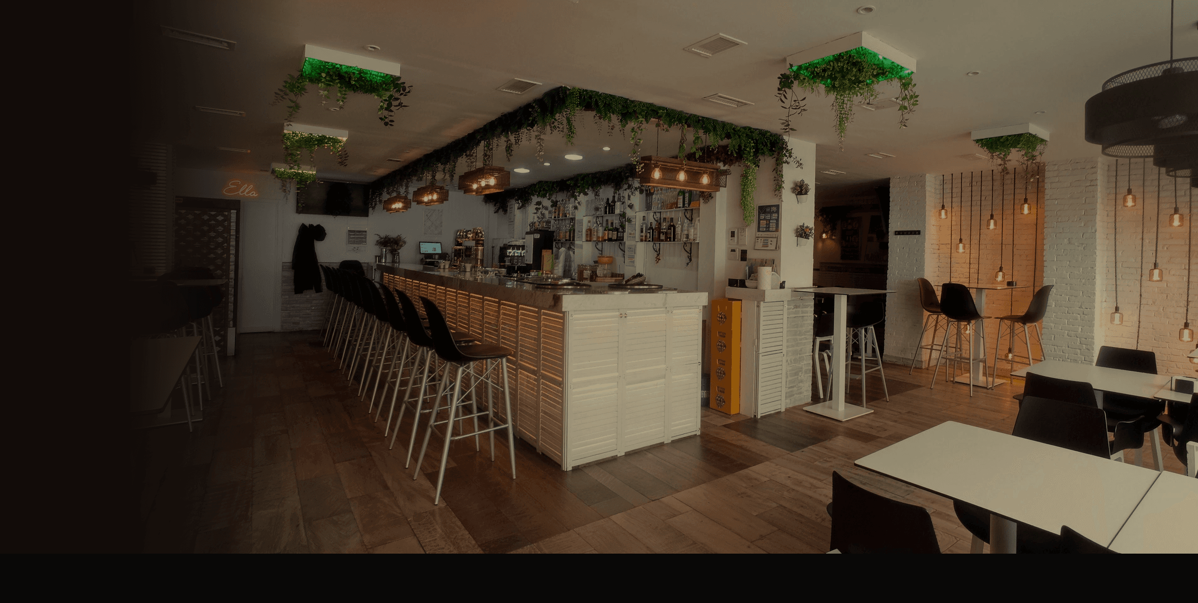 Interior de La Andaluza New de noche: barra blanca con plantas colgantes y lámparas cálidas