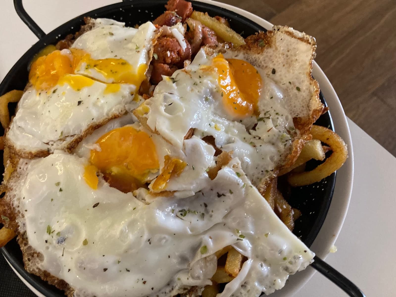 Huevos estrellados sobre patatas en sartén